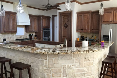 Mid-sized mountain style l-shaped dark wood floor and brown floor eat-in kitchen photo in Dallas with raised-panel cabinets, dark wood cabinets, granite countertops, beige backsplash, ceramic backsplash, stainless steel appliances and two islands