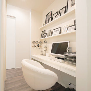 Photo of a small modern home office and library in Other with white walls, painted wood flooring, a built-in desk and grey floors.