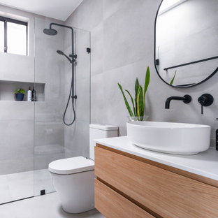 Mid-sized modern bathroom in Sydney with flat-panel cabinets, brown cabinets, gray tile, ceramic tile, ceramic floors, engineered quartz benchtops, grey floor, a hinged shower door, a niche, a single vanity, a floating vanity, a curbless shower, a two-piece toilet, a vessel sink and white benchtops.