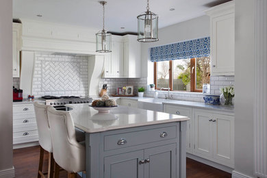 Photo of a traditional kitchen in Dublin with beaded inset cabinets, white cabinets, quartzite benchtops, white splashback, subway tile splashback, stainless steel appliances and light hardwood floors.