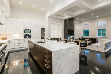 Large trendy l-shaped laminate floor and black floor kitchen photo in New Orleans with an undermount sink, flat-panel cabinets, white cabinets, marble countertops, white backsplash, stone slab backsplash, paneled appliances, an island and white countertops