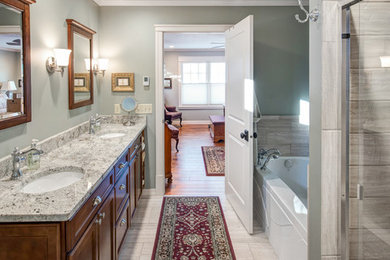 Inspiration for a large timeless 3/4 porcelain tile and beige floor bathroom remodel in Minneapolis with recessed-panel cabinets, dark wood cabinets, a two-piece toilet, gray walls, an undermount sink and granite countertops