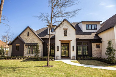 Inspiration for a large farmhouse beige two-story stone and board and batten exterior home remodel in Houston with a shingle roof and a brown roof