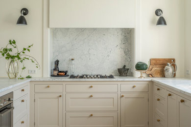 Inspiration for a mid-sized traditional u-shaped open plan kitchen in Aarhus with beige cabinets, marble benchtops, white splashback, marble splashback, medium hardwood floors, with island, brown floor and white benchtop.