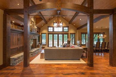 Living room - rustic open concept medium tone wood floor and brown floor living room idea in Seattle with beige walls, a standard fireplace, a stone fireplace and a media wall