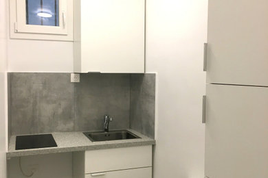 Cette image montre une petite cuisine traditionnelle en U avec un évier 1 bac, des portes de placard blanches, un plan de travail en stratifié, une crédence grise, une crédence en céramique, un sol en carrelage de céramique, un sol gris et un plan de travail gris.