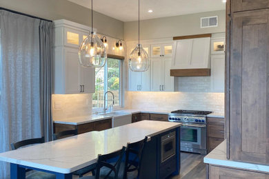 Mid-sized elegant u-shaped vinyl floor and brown floor eat-in kitchen photo in Orange County with a farmhouse sink, recessed-panel cabinets, medium tone wood cabinets, quartz countertops, white backsplash, porcelain backsplash, stainless steel appliances, an island and white countertops