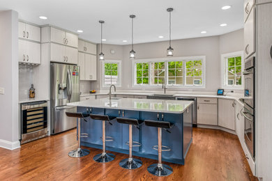 Kitchen - large modern u-shaped kitchen idea in DC Metro with a farmhouse sink, flat-panel cabinets, quartz countertops, stone tile backsplash, stainless steel appliances, an island and white countertops