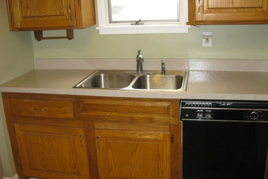 Kitchen - kitchen idea in Detroit with a double-bowl sink, raised-panel cabinets, medium tone wood cabinets and black appliances
