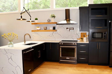 Inspiration for a mid-sized modern u-shaped light wood floor and brown floor enclosed kitchen remodel in Other with black cabinets, quartz countertops, black appliances, white countertops, an undermount sink, flat-panel cabinets, gray backsplash, stone slab backsplash and a peninsula