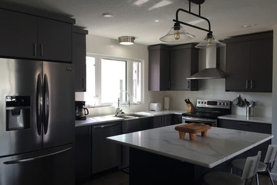 Example of a small minimalist vinyl floor eat-in kitchen design in Edmonton with a farmhouse sink, flat-panel cabinets, gray cabinets, quartzite countertops, white backsplash, subway tile backsplash, stainless steel appliances and an island