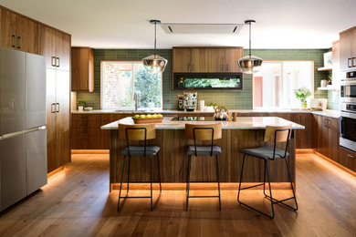 Example of a mid-century modern u-shaped medium tone wood floor and brown floor open concept kitchen design in Seattle with an undermount sink, flat-panel cabinets, medium tone wood cabinets, marble countertops, green backsplash, stainless steel appliances, an island and multicolored countertops