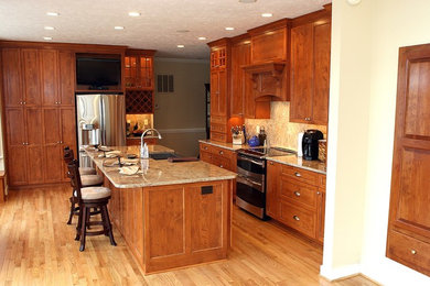 Large transitional light wood floor and brown floor kitchen photo in Richmond with a farmhouse sink, shaker cabinets, medium tone wood cabinets, granite countertops, beige backsplash, stone tile backsplash, stainless steel appliances and an island