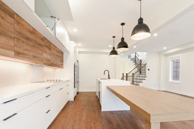 Inspiration for a modern single-wall medium tone wood floor kitchen remodel in Ottawa with flat-panel cabinets, white cabinets, white backsplash, subway tile backsplash, stainless steel appliances and an island