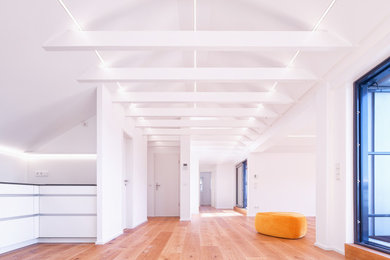 Imagen de salón abierto moderno con paredes blancas, suelo de madera en tonos medios, suelo marrón, vigas vistas y papel pintado