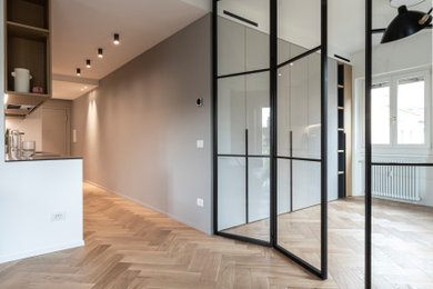 Imagen de salón abierto actual de tamaño medio con paredes grises y suelo de madera en tonos medios