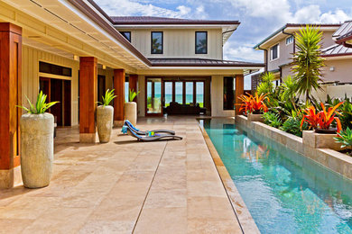 This is an example of a large tropical backyard patio in Hawaii with tile and a roof extension.