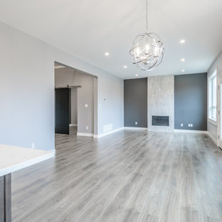 Idee per un soggiorno moderno di medie dimensioni e aperto con sala formale, pareti grigie, pavimento in laminato, camino classico, cornice del camino piastrellata e pavimento grigio