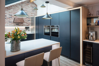 Ejemplo de cocinas en U minimalista con armarios con paneles lisos, puertas de armario azules, encimera de acrílico, península y encimeras blancas