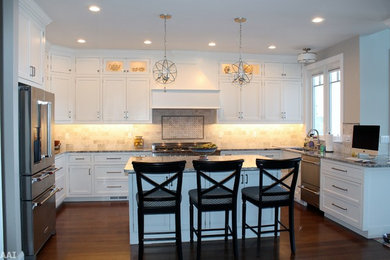 Inspiration for a large timeless u-shaped medium tone wood floor and brown floor open concept kitchen remodel in New York with an undermount sink, shaker cabinets, white cabinets, granite countertops, beige backsplash, marble backsplash, stainless steel appliances and an island