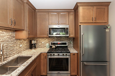 Eat-in kitchen - mid-sized transitional l-shaped laminate floor and brown floor eat-in kitchen idea in Chicago with an undermount sink, recessed-panel cabinets, light wood cabinets, granite countertops, brown backsplash, glass tile backsplash, stainless steel appliances, an island and beige countertops