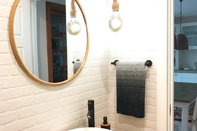 Foto de aseo escandinavo pequeño con armarios abiertos, puertas de armario de madera oscura, sanitario de una pieza, baldosas y/o azulejos blancos, baldosas y/o azulejos de cerámica, paredes multicolor, suelo de madera clara, lavabo sobreencimera y encimera de madera