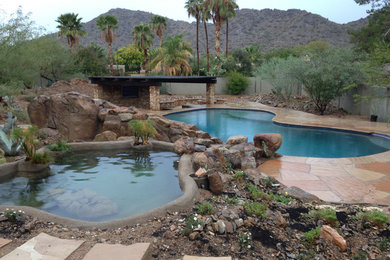 Inspiration for a mid-sized backyard custom-shaped lap pool in Phoenix with a hot tub and natural stone pavers.