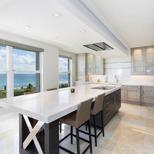 На фото: класса люкс маленькие угловые кухни-гостиные в стиле современная классика с фасадами с утопленной филенкой, бежевыми фасадами, белым фартуком, островом, бежевым полом, белой столешницей, тройной раковиной, мраморной столешницей, фартуком из мрамора, техникой из нержавеющей стали и полом из керамогранита