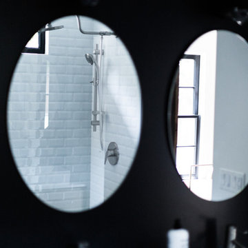 Oval Bath Mirrors on Dramatic Black Wall, White Subway Tile