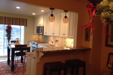 Country porcelain tile kitchen photo in Other with a single-bowl sink, recessed-panel cabinets, distressed cabinets, granite countertops, yellow backsplash, glass sheet backsplash, stainless steel appliances and an island