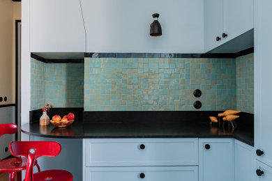 Idées déco pour une petite cuisine ouverte encastrable et haussmannienne rétro en U avec un évier encastré, un placard à porte plane, des portes de placard bleues, un plan de travail en granite, une crédence bleue, une crédence en céramique, carreaux de ciment au sol, un sol multicolore et plan de travail noir.