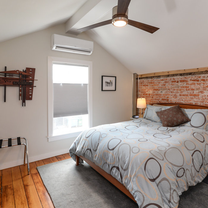 Bedroom - mid-sized rustic loft-style medium tone wood floor and brown floor bedroom idea in Detroit with white walls
