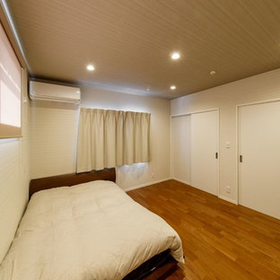 Immagine di una camera matrimoniale etnica di medie dimensioni con pareti bianche, pavimento in legno verniciato e pavimento marrone