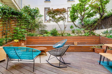 Cette photo montre une terrasse arrière et au rez-de-chaussée tendance de taille moyenne avec des solutions pour vis-à-vis et un garde-corps en bois.