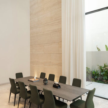 Dining room beneath a double-height travertine wall, Dubai villa