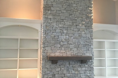 Minimalist dark wood floor and brown floor living room photo in Miami with beige walls, a standard fireplace and a stone fireplace