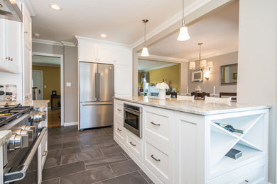 Mid-sized cottage l-shaped ceramic tile and gray floor eat-in kitchen photo in New York with a farmhouse sink, shaker cabinets, yellow cabinets, granite countertops, gray backsplash, glass tile backsplash, stainless steel appliances and an island