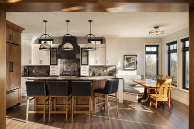 Example of a large transitional l-shaped medium tone wood floor and brown floor enclosed kitchen design in Calgary with recessed-panel cabinets, white cabinets, granite countertops, gray backsplash, glass tile backsplash, paneled appliances and an island