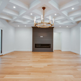 Großes, Offenes Klassisches Wohnzimmer mit weißer Wandfarbe, hellem Holzboden, Kamin, Kaminumrandung aus Holzdielen, gelbem Boden und Kassettendecke in Charlotte