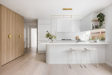 Inspiration for a mid-sized modern u-shaped eat-in kitchen in Sydney with quartz benchtops, white splashback, engineered quartz splashback, black appliances and a peninsula.