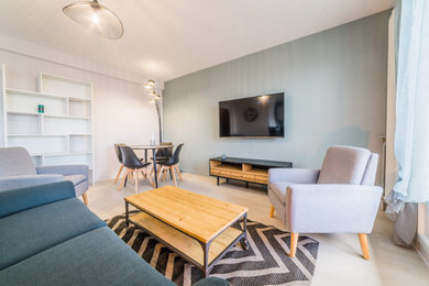 Cette image montre une salle de séjour minimaliste de taille moyenne et ouverte avec un mur vert, sol en stratifié et un téléviseur fixé au mur.