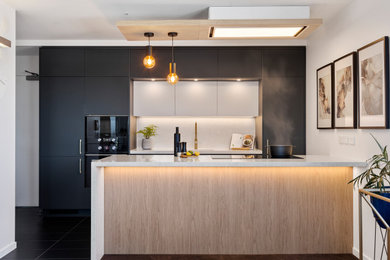 Mid-sized transitional galley open plan kitchen in Brisbane with an undermount sink, turquoise cabinets, quartz benchtops, white splashback, engineered quartz splashback, black appliances, a peninsula and white benchtop.