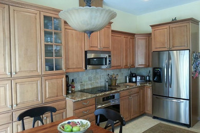 Example of a mid-sized classic galley porcelain tile open concept kitchen design in Sacramento with a double-bowl sink, raised-panel cabinets, medium tone wood cabinets, granite countertops, green backsplash, ceramic backsplash, stainless steel appliances and a peninsula