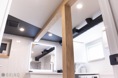 Inspiration for a mid-sized industrial porcelain tile and white floor laundry room remodel in Toronto with a single-bowl sink, flat-panel cabinets, white cabinets, quartz countertops, white backsplash, subway tile backsplash, black walls, a side-by-side washer/dryer and white countertops