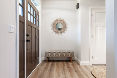 トロントにある高級な中くらいなカントリー風のおしゃれな玄関ドア (白い壁、ラミネートの床、濃色木目調のドア、茶色い床) の写真
