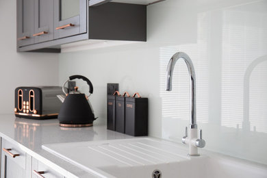 Mid-sized single-wall open plan kitchen in Other with an integrated sink, shaker cabinets, grey cabinets, quartzite benchtops, white splashback, glass sheet splashback and white benchtop.