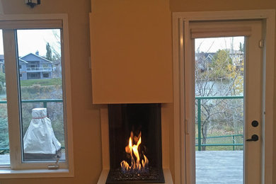 Example of a mid-sized classic enclosed dark wood floor and brown floor living room design in Edmonton with beige walls, a hanging fireplace and a plaster fireplace
