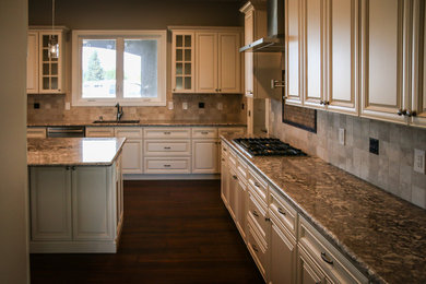 Design ideas for a large traditional u-shaped kitchen in Sacramento with an undermount sink, raised-panel cabinets, white cabinets, granite benchtops, grey splashback, stone tile splashback, stainless steel appliances, dark hardwood floors, with island and brown floor.