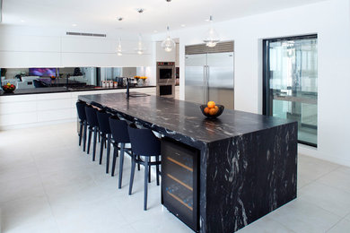 Large contemporary galley separate kitchen in Sydney with an undermount sink, flat-panel cabinets, white cabinets, granite benchtops, mirror splashback, stainless steel appliances, marble floors, no island, white floor and black benchtop.