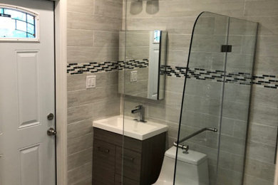 Small trendy master gray tile and ceramic tile ceramic tile, gray floor, single-sink and wainscoting bathroom photo in Miami with flat-panel cabinets, dark wood cabinets, a one-piece toilet, gray walls, an integrated sink, solid surface countertops, a hinged shower door, white countertops and a freestanding vanity